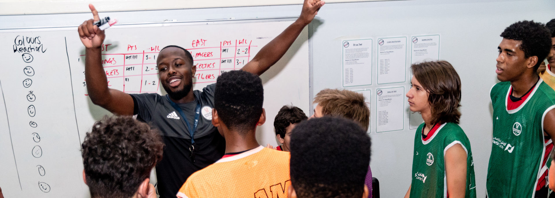 Coach Core apprentice Terrell stands in front of whiteboard surrounded by children